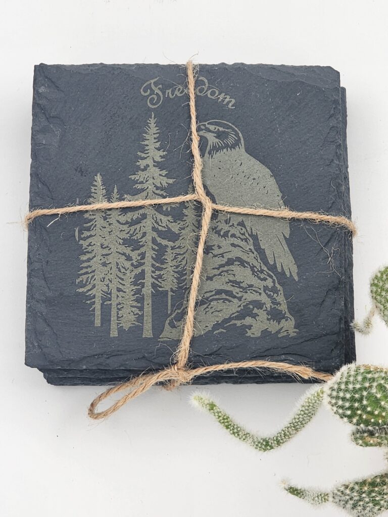 Laser-engraved slate coaster set featuring an eagle and forest design
